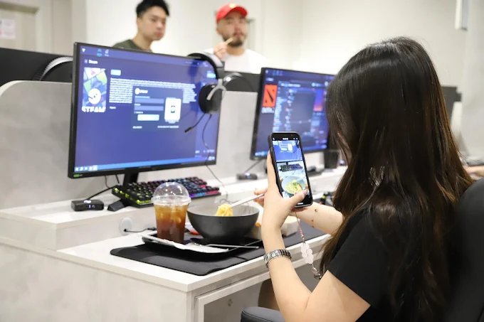 A customer photographing her noodle bowl and iced drink at her PC desk